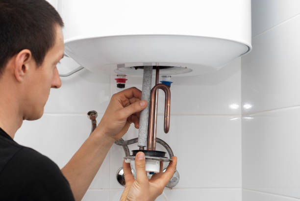 master installs a new electric heating ten in a water tank